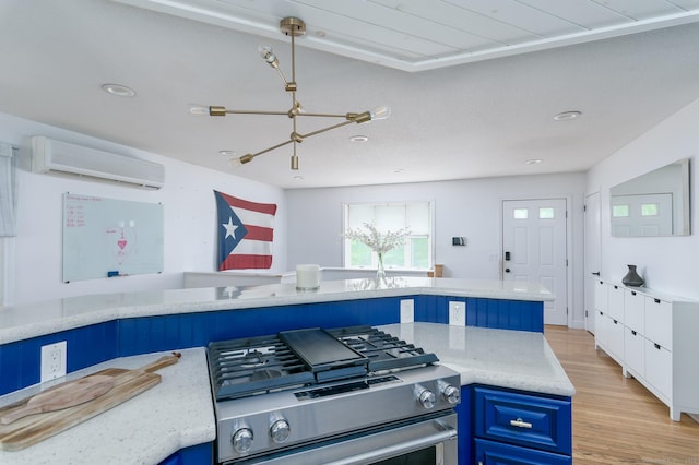 104 E St, Hebron, CT 06248 - kitchen featuring blue cabinetry, a wall unit AC, stainless steel gas range oven, light wood-style floors, and a chandelier