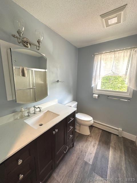 149 Mill Hill Rd, Colchester, CT 06415 - bathroom with a baseboard heating unit, vanity, a textured ceiling, wood finished floors, and toilet