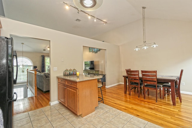354 Lynne Pl, Bridgeport, CT 06610 - kitchen featuring freestanding refrigerator, rail lighting, lofted ceiling, light tile patterned flooring, and brown cabinets