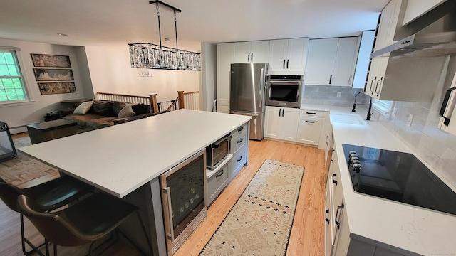 550 W Lake Ave, Guilford, CT 06437 - kitchen featuring appliances with stainless steel finishes, exhaust hood, light wood-type flooring, and a sink