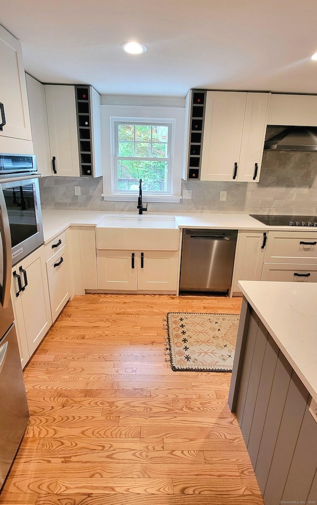 550 W Lake Ave, Guilford, CT 06437 - kitchen featuring stainless steel appliances, a sink, light wood finished floors, decorative backsplash, and white cabinets