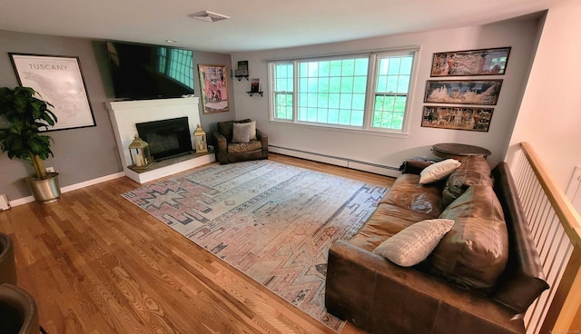 550 W Lake Ave, Guilford, CT 06437 - living area with baseboard heating, wood finished floors, a glass covered fireplace, and baseboards