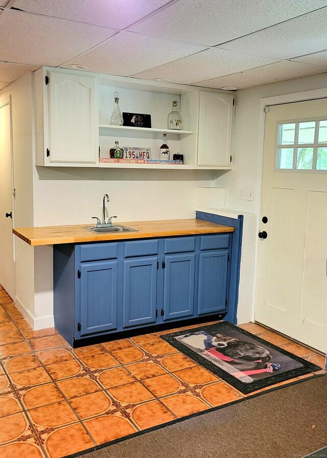 550 W Lake Ave, Guilford, CT 06437 - kitchen featuring blue cabinetry, a sink, open shelves, wooden counters, and a drop ceiling