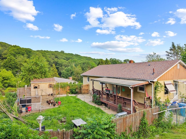 24 Ledgewood Ct, Norwich, CT 06360 - back of house with a fenced backyard, board and batten siding, an outbuilding, a chimney, and a wooded view