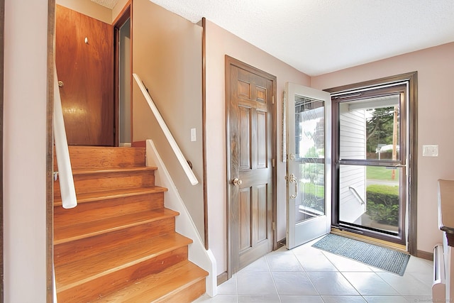47 Delmont Rd, East Hartford, CT 06108 - entrance foyer with light tile patterned floors, baseboards, a textured ceiling, and stairway