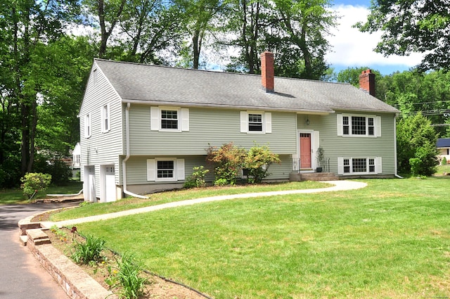 83 Elizabeth St, South Windsor, CT 06074 - raised ranch with a chimney, asphalt driveway, a front lawn, and an attached garage