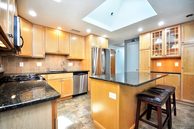83 Elizabeth St, South Windsor, CT 06074 - kitchen with stainless steel appliances, a sink, light brown cabinetry, decorative backsplash, and a kitchen breakfast bar