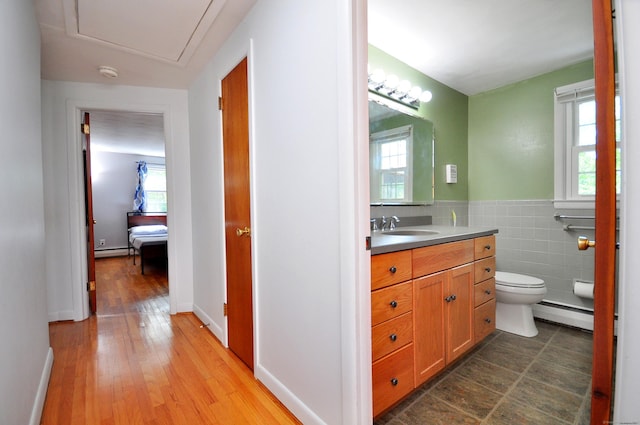 83 Elizabeth St, South Windsor, CT 06074 - bathroom with a baseboard heating unit, vanity, toilet, wood finished floors, and tile walls