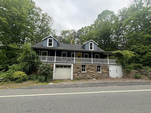 29 Middle Tpke, Mansfield, CT 06268 - view of front of house featuring stone siding, an attached garage, covered porch, and view of scattered trees