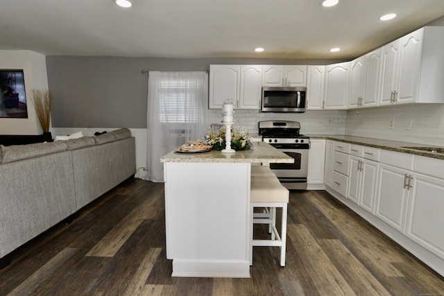 155 Cedar St, New Haven, CT 06519 - kitchen with stainless steel appliances, a kitchen bar, white cabinetry, a kitchen island, and a wainscoted wall