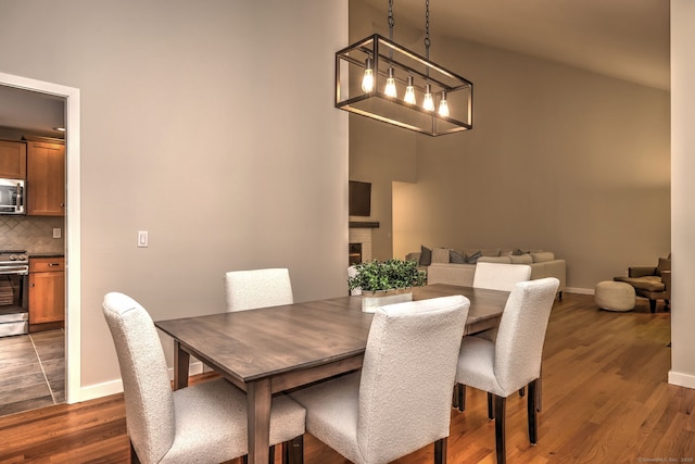 690 Forest Rd Unit 442, West Haven, CT 06516 - dining area with dark wood-style floors, baseboards, a high ceiling, and a fireplace