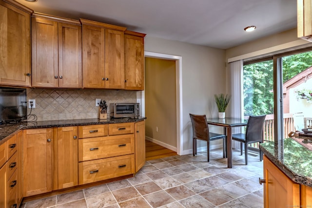 690 Forest Rd Unit 442, West Haven, CT 06516 - kitchen with tasteful backsplash, baseboards, light stone finish flooring, dark stone counters, and brown cabinets