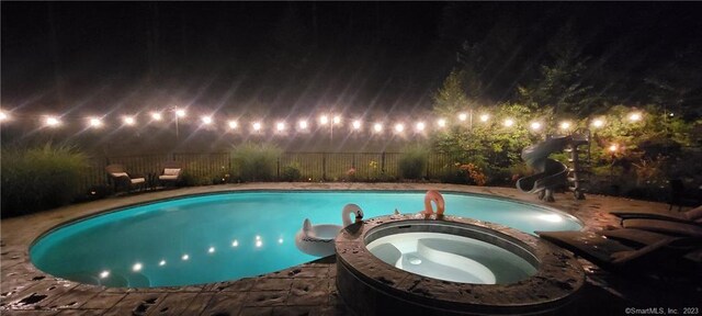 36 Old Johnson Ln, Middletown, CT 06457 - pool at night with a water slide, a pool with connected hot tub, and a fenced backyard