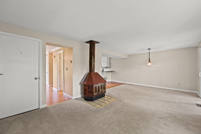 36 Wood Duck Ln Unit 36, Simsbury, CT 06081 - unfurnished living room featuring carpet, a wood stove, and baseboards