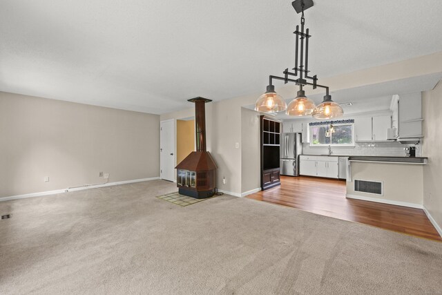 36 Wood Duck Ln Unit 36, Simsbury, CT 06081 - unfurnished living room featuring carpet, a wood stove, a sink, and baseboards