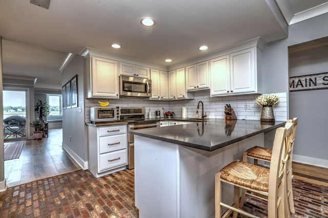 714 Popes Island Rd Unit 714, Milford, CT 06461 - kitchen with appliances with stainless steel finishes, dark countertops, baseboards, a sink, and brick floors