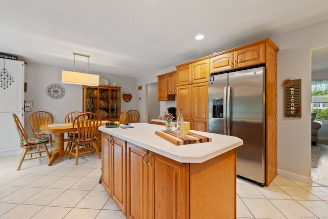 19 Ridgeview Dr, Ellington, CT 06029 - kitchen featuring stainless steel fridge, light tile patterned floors, a center island, light countertops, and brown cabinetry