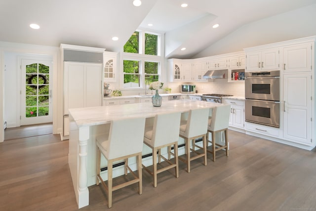 50 Parish Rd N, New Canaan, CT 06840 - kitchen featuring appliances with stainless steel finishes, under cabinet range hood, vaulted ceiling, white cabinetry, and a center island