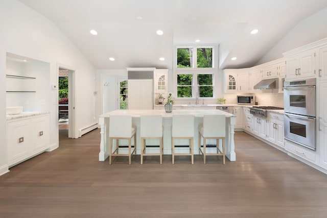 50 Parish Rd N, New Canaan, CT 06840 - kitchen with lofted ceiling, stainless steel appliances, baseboard heating, white cabinetry, and a breakfast bar area