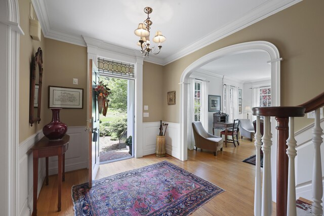 52 Dug Rd, Glastonbury, CT 06073 - foyer with arched walkways, a chandelier, light wood finished floors, crown molding, and wainscoting