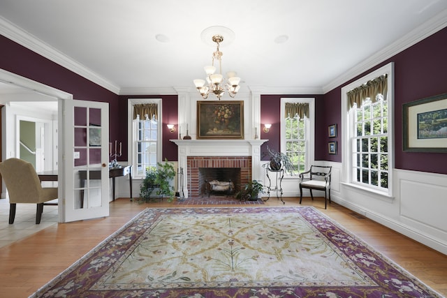 52 Dug Rd, Glastonbury, CT 06073 - living room with a chandelier, crown molding, wood finished floors, a wainscoted wall, and a brick fireplace