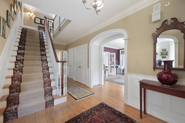 52 Dug Rd, Glastonbury, CT 06073 - entryway featuring arched walkways, crown molding, wood finished floors, stairway, and wainscoting