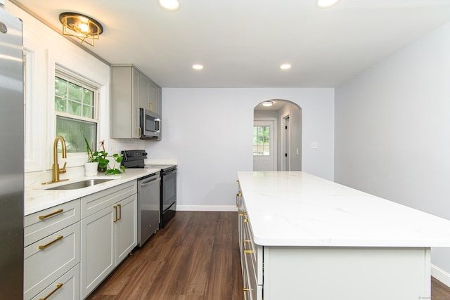 163 State Ave, Killingly, CT 06241 - kitchen with stainless steel appliances, gray cabinets, a center island, arched walkways, and dark wood-style flooring