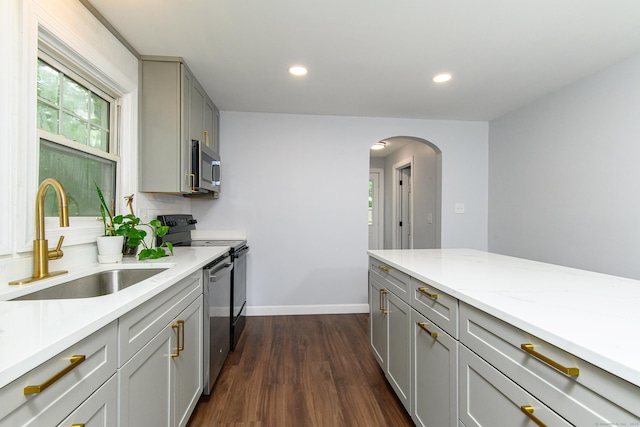 163 State Ave, Killingly, CT 06241 - kitchen featuring gray cabinetry, appliances with stainless steel finishes, arched walkways, dark wood finished floors, and light stone counters