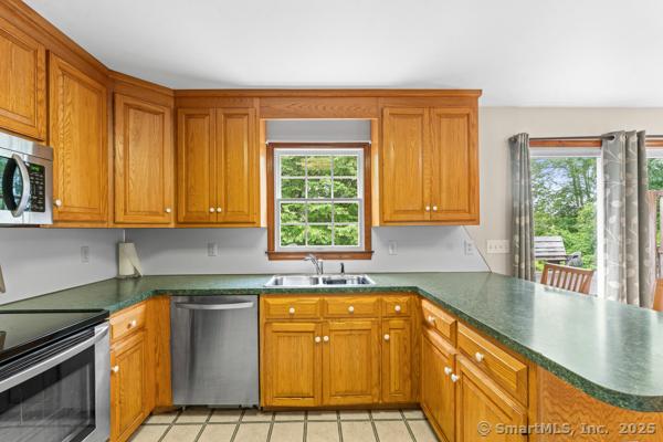 5 Conrad Ct, Ledyard, CT 06335 - kitchen with stainless steel appliances, a sink, a peninsula, brown cabinetry, and dark countertops