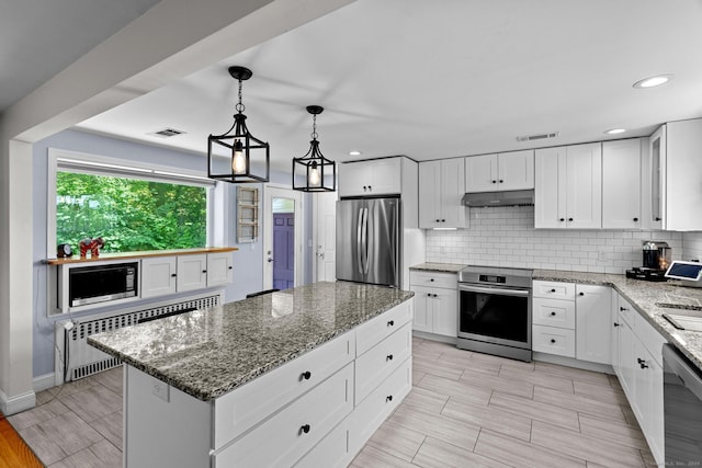 401 Russell Ave, Suffield, CT 06078 - kitchen with appliances with stainless steel finishes, decorative backsplash, a kitchen island, light stone countertops, and recessed lighting