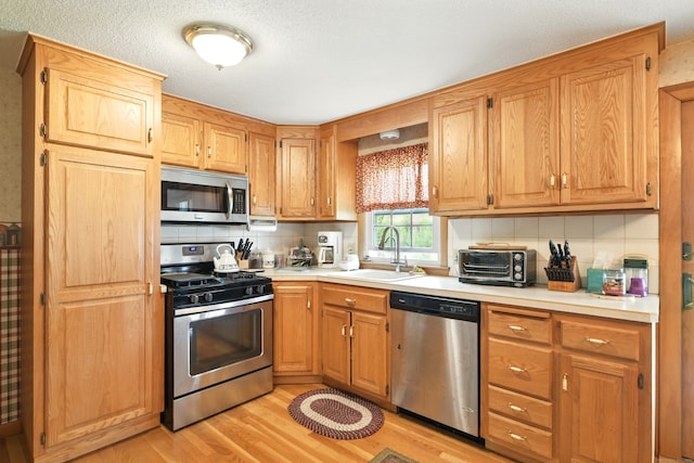 47 Varno Ln, Enfield, CT 06082 - kitchen with appliances with stainless steel finishes, a sink, decorative backsplash, and light wood finished floors