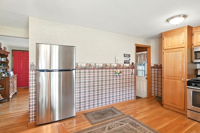 47 Varno Ln, Enfield, CT 06082 - kitchen featuring stainless steel appliances, wallpapered walls, light wood-style floors, wainscoting, and a textured ceiling