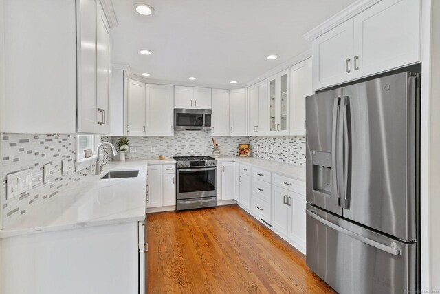 50 Harrison Ave, New Canaan, CT 06840 - kitchen featuring stainless steel appliances, a sink, white cabinetry, backsplash, and light wood-style flooring