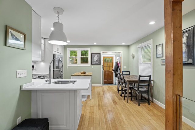 128 Mill River St, New Haven, CT 06511 - kitchen featuring light wood-style flooring, light countertops, a peninsula, baseboards, and a sink