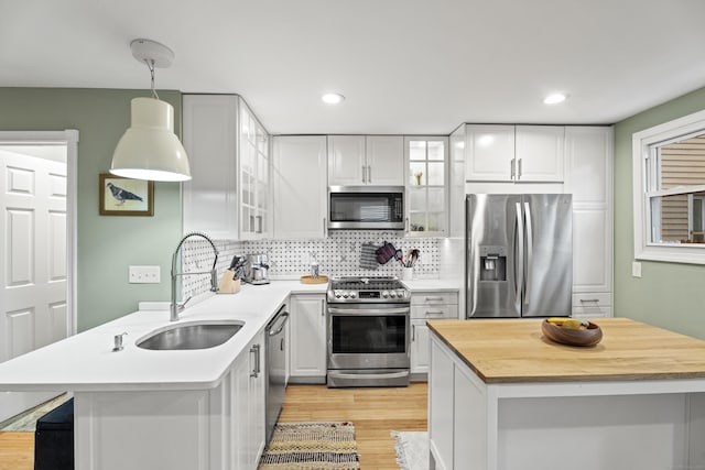 128 Mill River St, New Haven, CT 06511 - kitchen featuring appliances with stainless steel finishes, a sink, light wood finished floors, tasteful backsplash, and glass insert cabinets