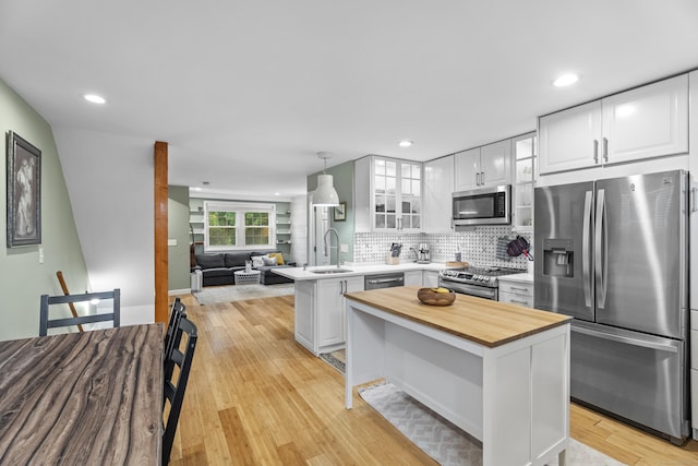128 Mill River St, New Haven, CT 06511 - kitchen with appliances with stainless steel finishes, butcher block countertops, a peninsula, glass insert cabinets, and decorative backsplash