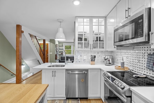 128 Mill River St, New Haven, CT 06511 - kitchen featuring appliances with stainless steel finishes, a sink, white cabinets, light countertops, and a peninsula