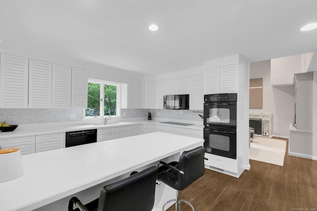 14 The Mews, Westport, CT 06880 - kitchen featuring black appliances, a kitchen breakfast bar, dark wood-type flooring, light countertops, and recessed lighting
