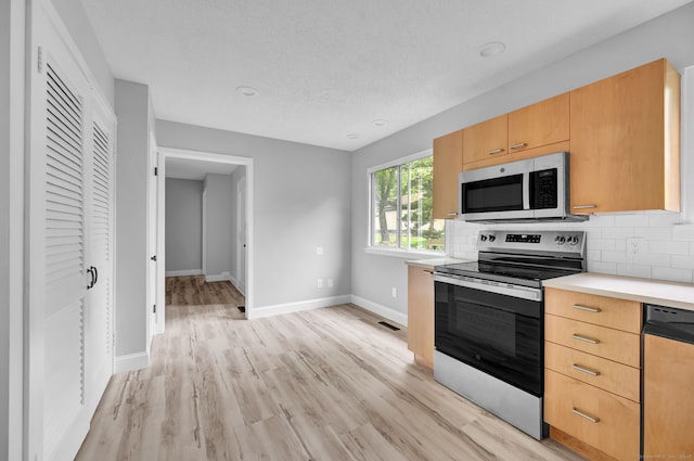 170 Heritage Vlg Unit B, Southbury, CT 06488 - kitchen featuring appliances with stainless steel finishes, baseboards, light countertops, light wood-type flooring, and decorative backsplash