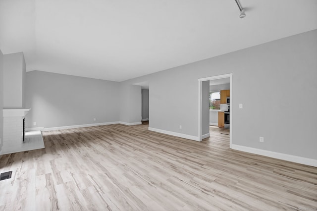 170 Heritage Vlg Unit B, Southbury, CT 06488 - unfurnished living room with light wood-style floors, a brick fireplace, baseboards, and lofted ceiling