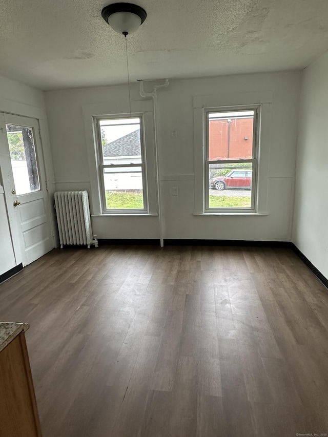47 Holl St, Manchester, CT 06040 - unfurnished dining area featuring radiator heating unit, wood finished floors, a textured ceiling, and baseboards