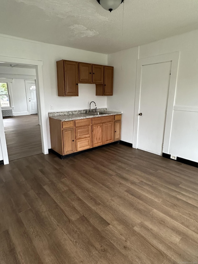47 Holl St, Manchester, CT 06040 - kitchen with a sink, dark wood-style floors, baseboards, brown cabinetry, and a textured ceiling