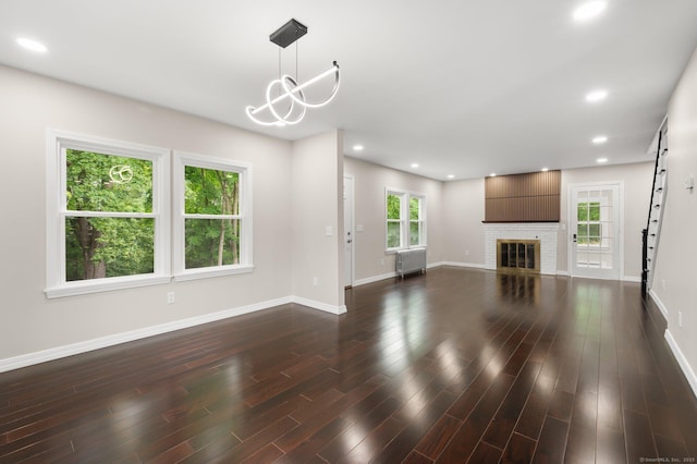 56 Uncas Ave, New London, CT 06320 - unfurnished living room featuring radiator, baseboards, dark wood-type flooring, recessed lighting, and a brick fireplace