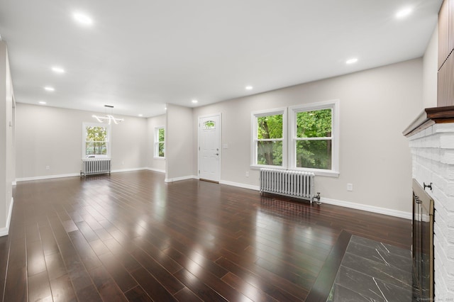 56 Uncas Ave, New London, CT 06320 - unfurnished living room with radiator, a brick fireplace, a chandelier, wood finished floors, and recessed lighting