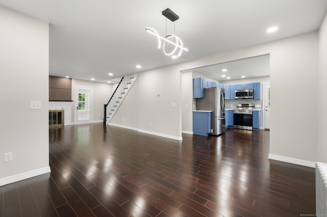 56 Uncas Ave, New London, CT 06320 - unfurnished living room with a chandelier, baseboards, a brick fireplace, stairway, and recessed lighting