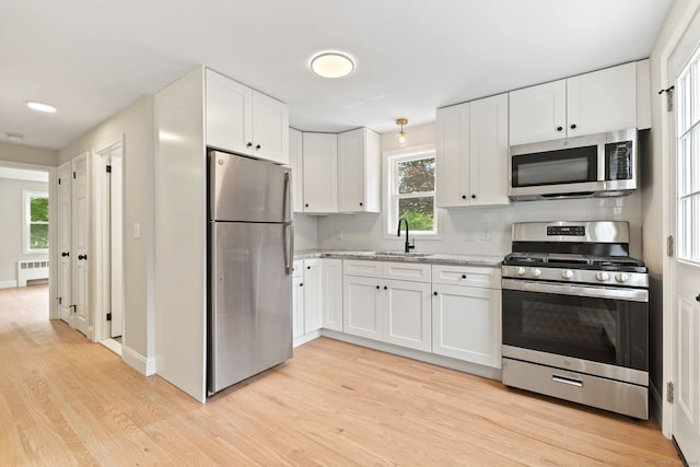 1357 Slater Rd, New Britain, CT 06053 - kitchen with stainless steel appliances, radiator, a sink, light wood-type flooring, and white cabinets