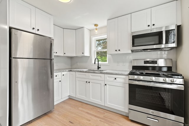 1357 Slater Rd, New Britain, CT 06053 - kitchen with appliances with stainless steel finishes, a sink, white cabinetry, and decorative backsplash