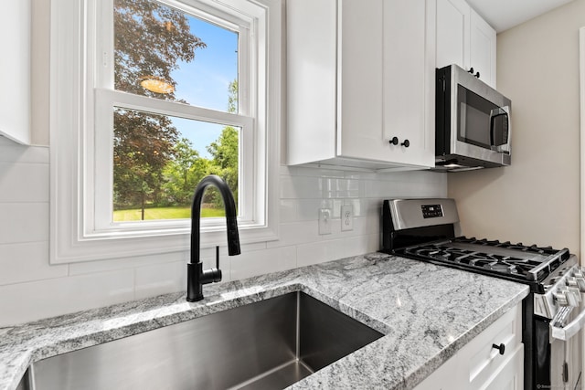 1357 Slater Rd, New Britain, CT 06053 - kitchen featuring appliances with stainless steel finishes, a sink, backsplash, and white cabinets