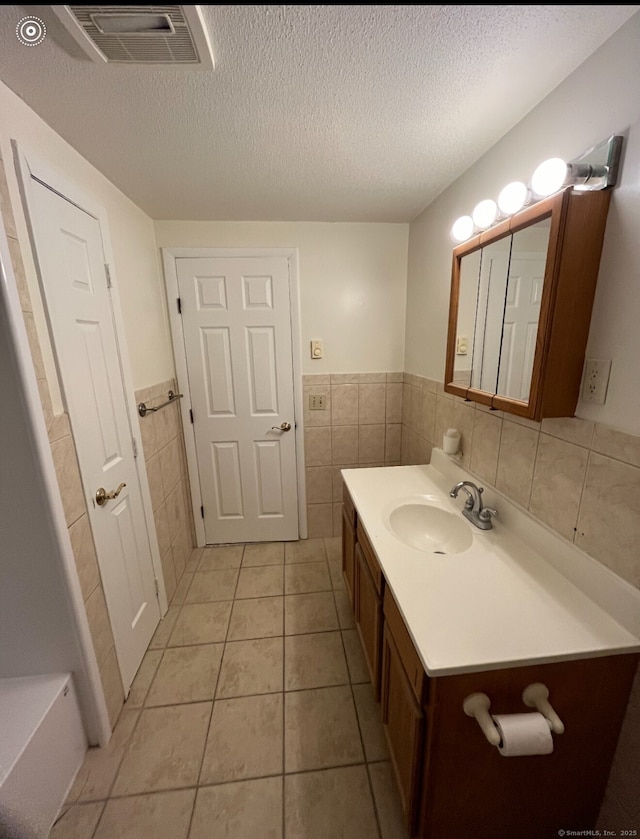 188 Judith Ln, Waterbury, CT 06704 - bathroom featuring tile walls, vanity, a wainscoted wall, a textured ceiling, and tile patterned flooring