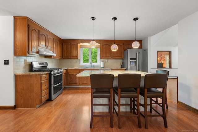 80 Farmstead Ln, Windsor, CT 06095 - kitchen featuring stainless steel appliances, a sink, under cabinet range hood, brown cabinets, and a center island